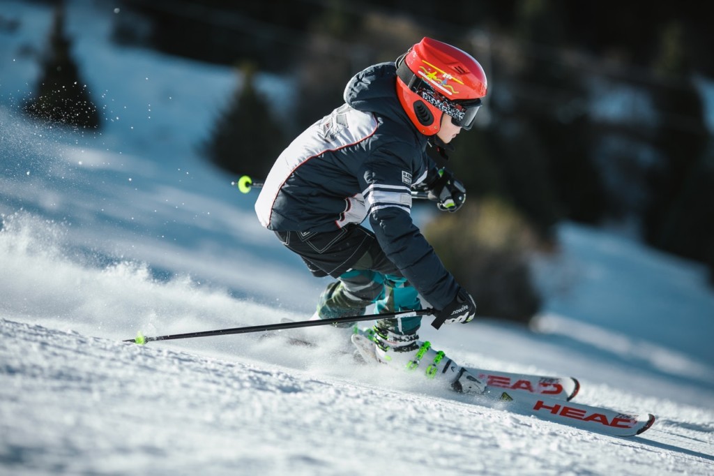 Kid downhill skiing with red helmet