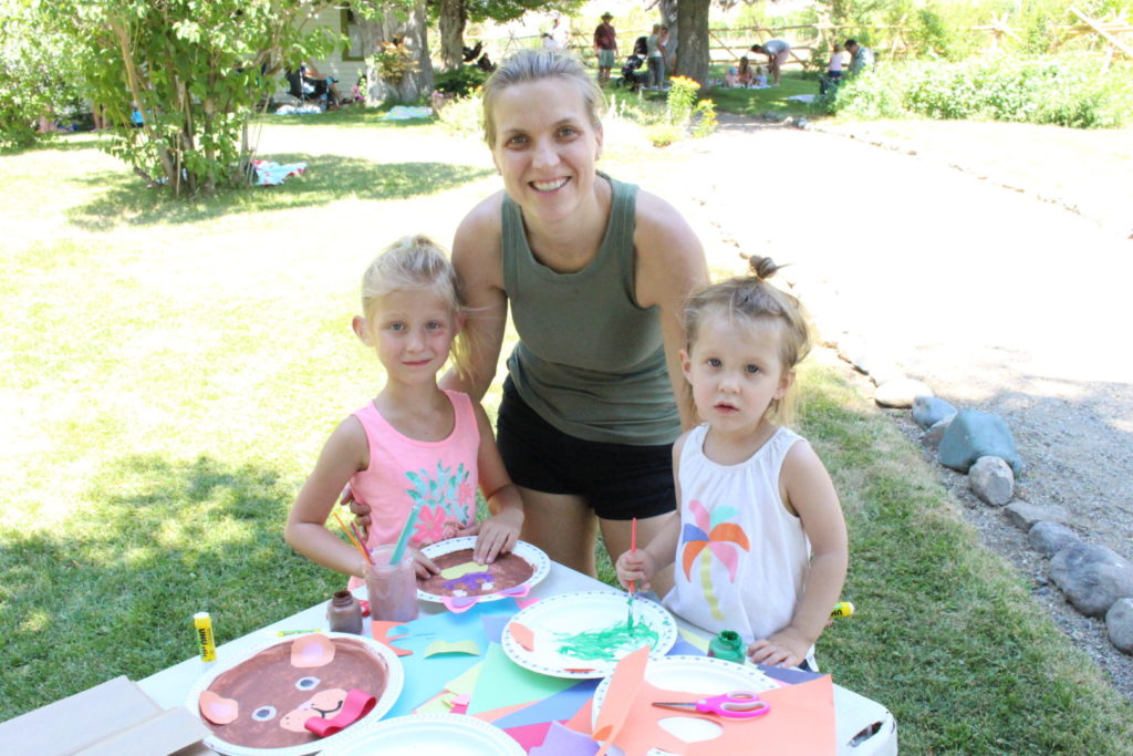 Mom with girls at the Grist Mill and Gardens in Keremeos. Standing in front of a table with paper plate teddy bear crafts in front of them.